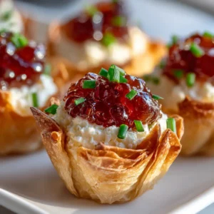 Cranberry Pepper Jelly Appetizer: The Easiest Holiday Recipe 4 A close-up shot of cranberry pepper jelly being spooned over a block of cream cheese, showing the texture and vibrant color.