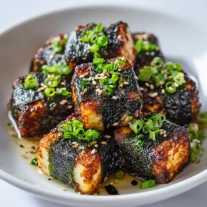 A close-up shot of nori-wrapped tofu pieces before being cooked. The focus is on the texture of the tofu and the dark seaweed belt around it.
