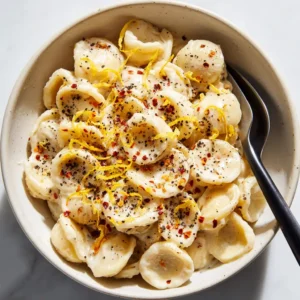 Creamy Roast Garlic and Lemon Pasta with Orecchiette 3 Close-up of orecchiette pasta covered in a thick light-beige cream sauce with lemon zest. (Creamy Roast Garlic and Lemon Pasta)